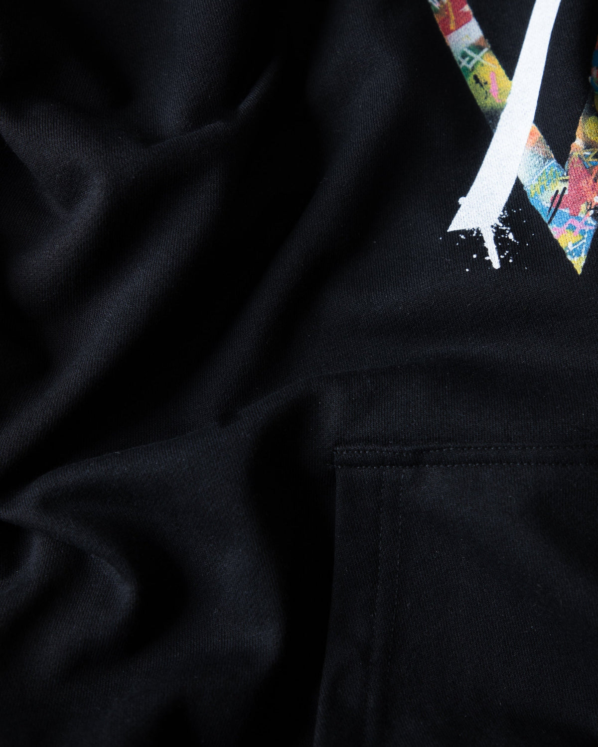 Alan Walker Tired 0 Hoodie sleeve and pocket close-up, black fleece beside the multicoloured AW chest print