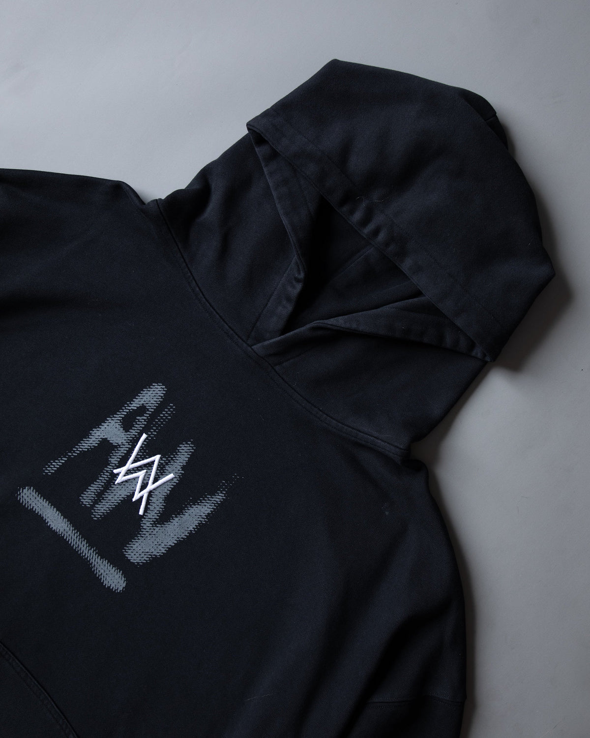 Alan Walker Faded Graffiti Hoodie in black, angled shot of the hood above the brushed grey AW chest tag