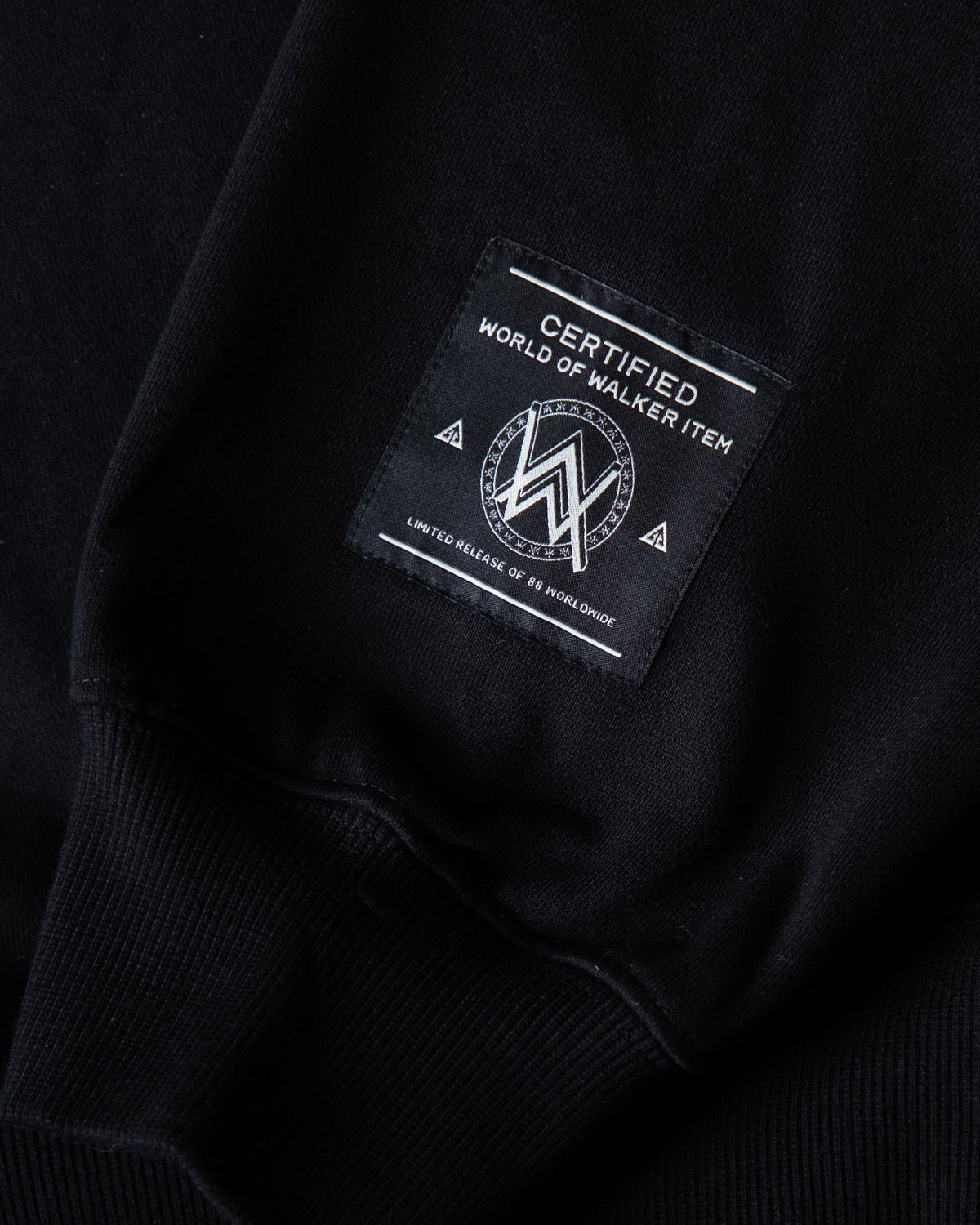 Alan Walker Tired 0 Hoodie hem label close-up, black Walker tag stitched above the ribbed cuff