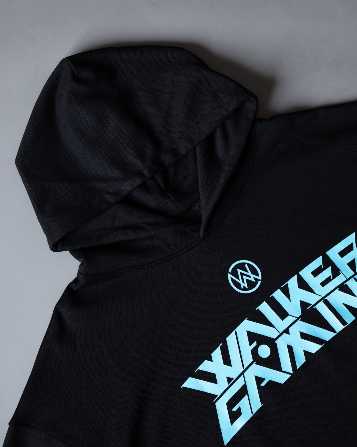 Alan Walker Gaming Hoodie angled flat lay, black hood beside the diagonal blue Walker Gaming print