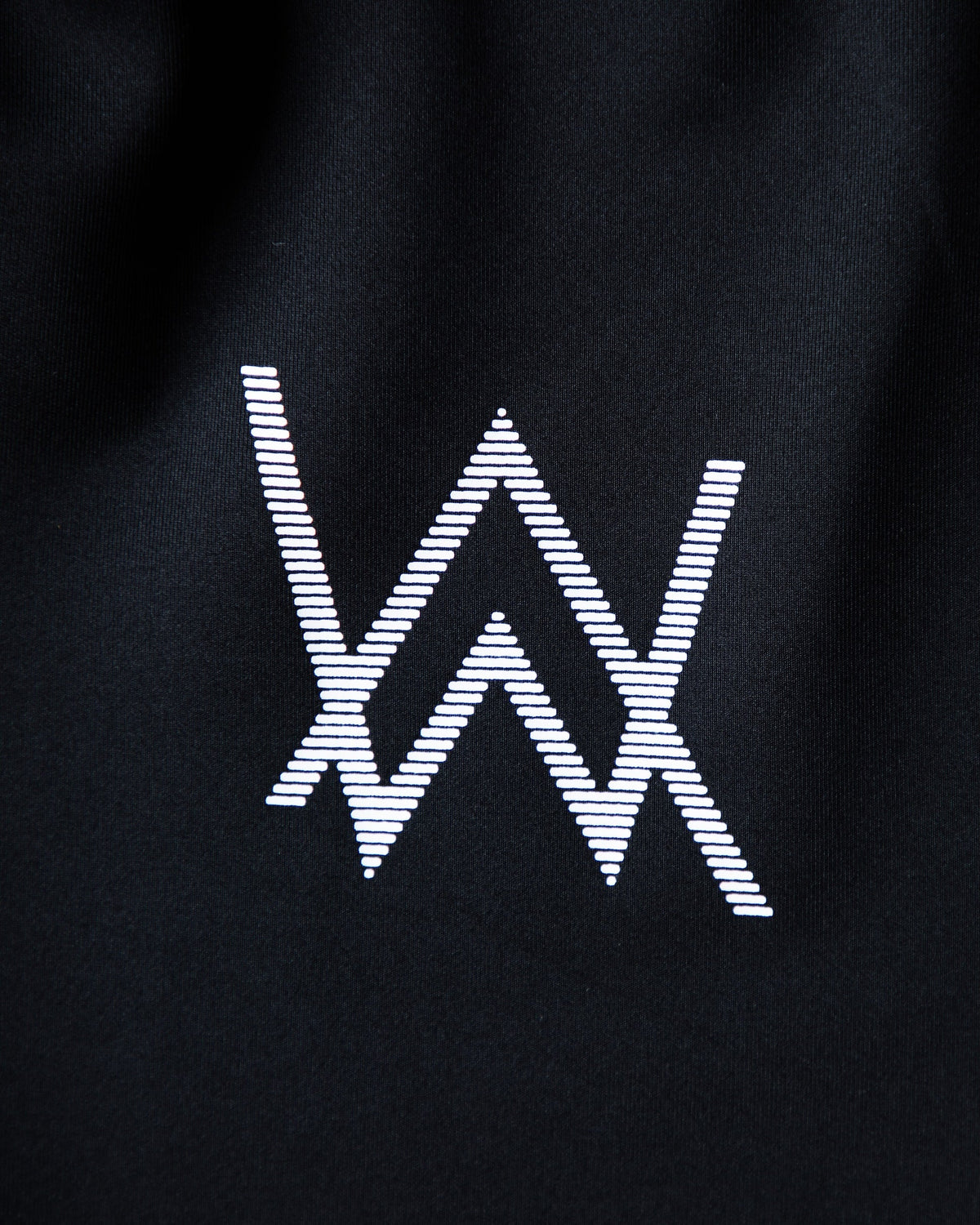 Alan Walker World of Walker Skyline Sweatpants leg print close-up, striped white AW logo on black tech fabric