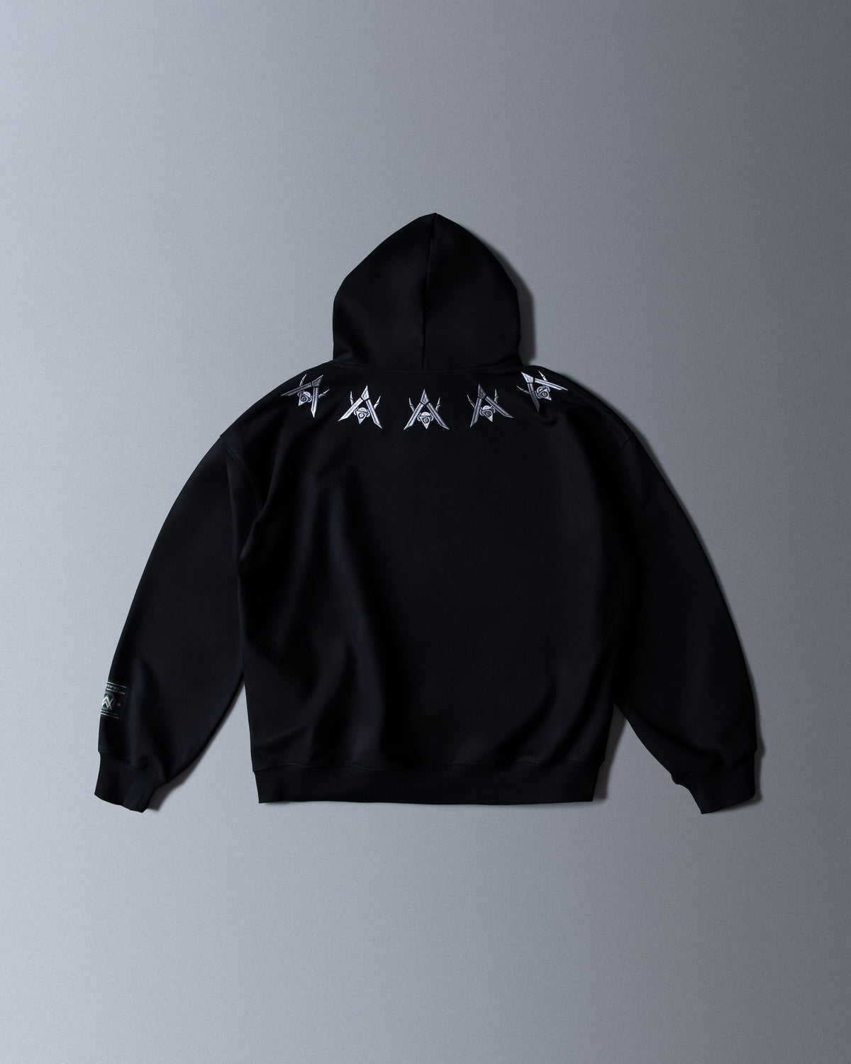 Alan Walker Watch The Drone Hoodie back flat lay, silver drone glyphs across the shoulders on black cotton