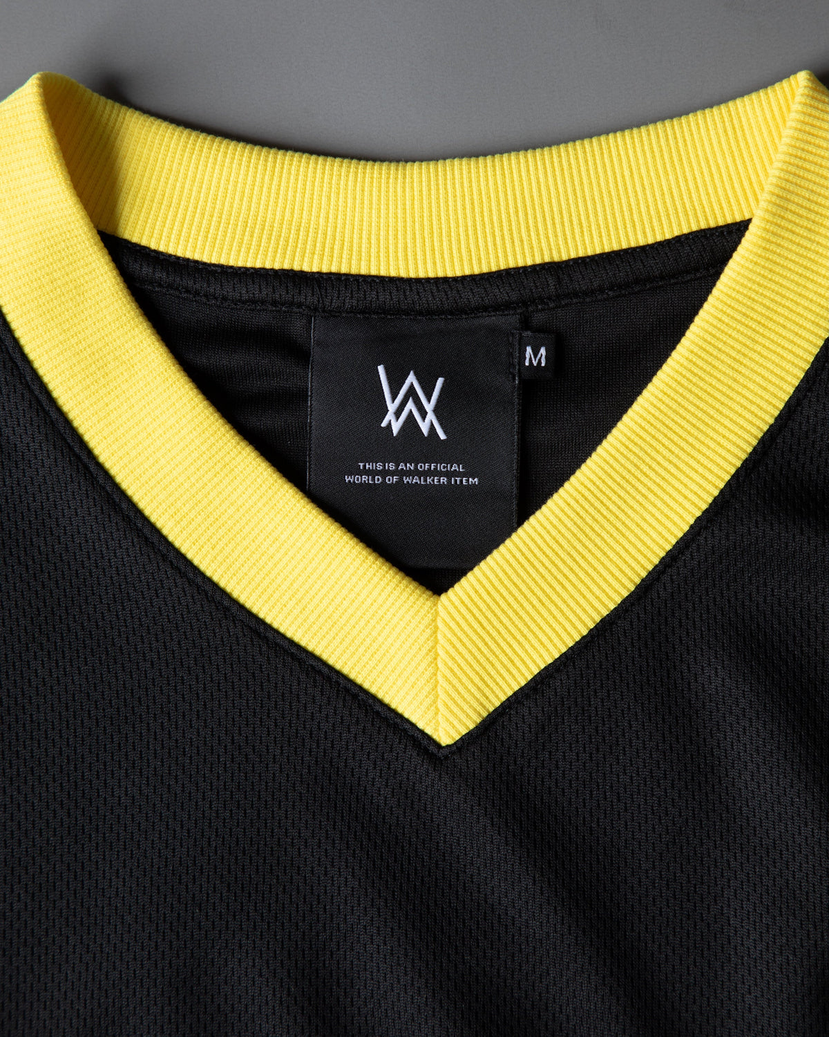 Alan Walker CheckPoint One Tribe Jersey neckline close-up, bright yellow V-neck rib and black AW neck tag
