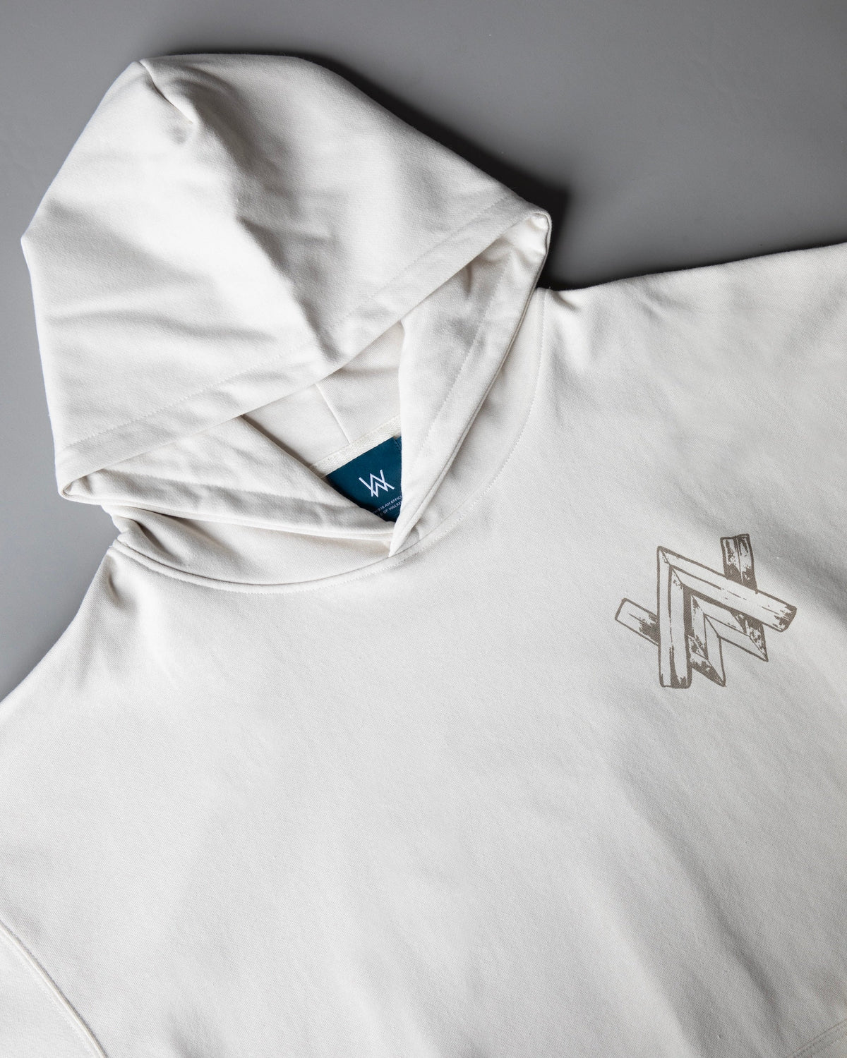 Alan Walker Encyclopedia Hoodie close-up of the off white hood, navy AW neck tag and sketched chest print