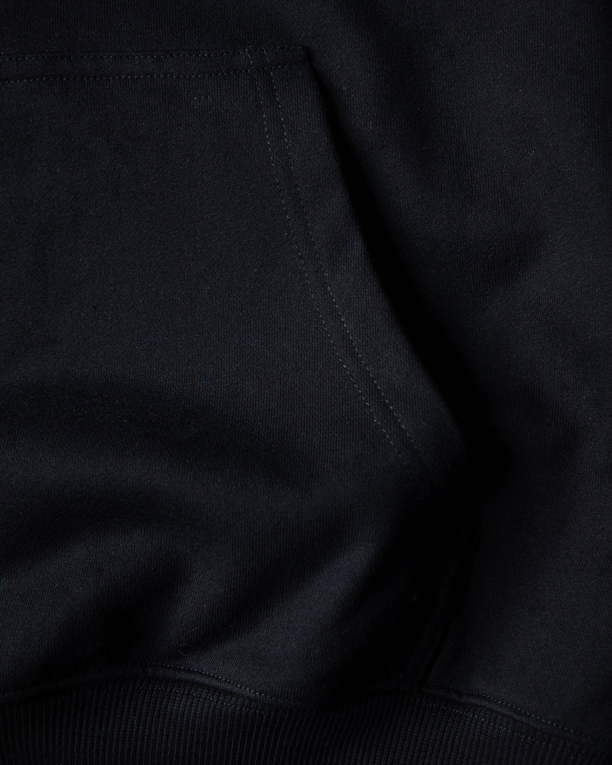 Alan Walker World of Walker Skyline Hoodie pocket and hem close-up showing the soft black fabric and stitching