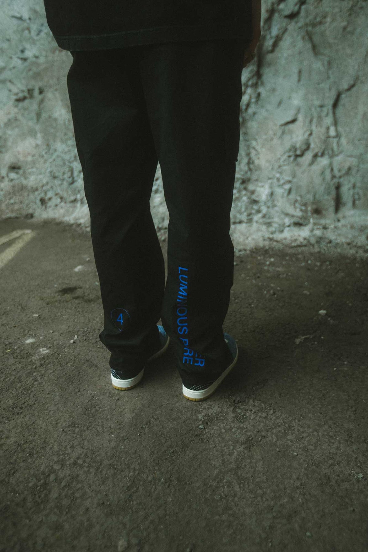Alan Walker Drone Repair Shop Cargo Pants worn on a rocky path, blue leg print catching the daylight