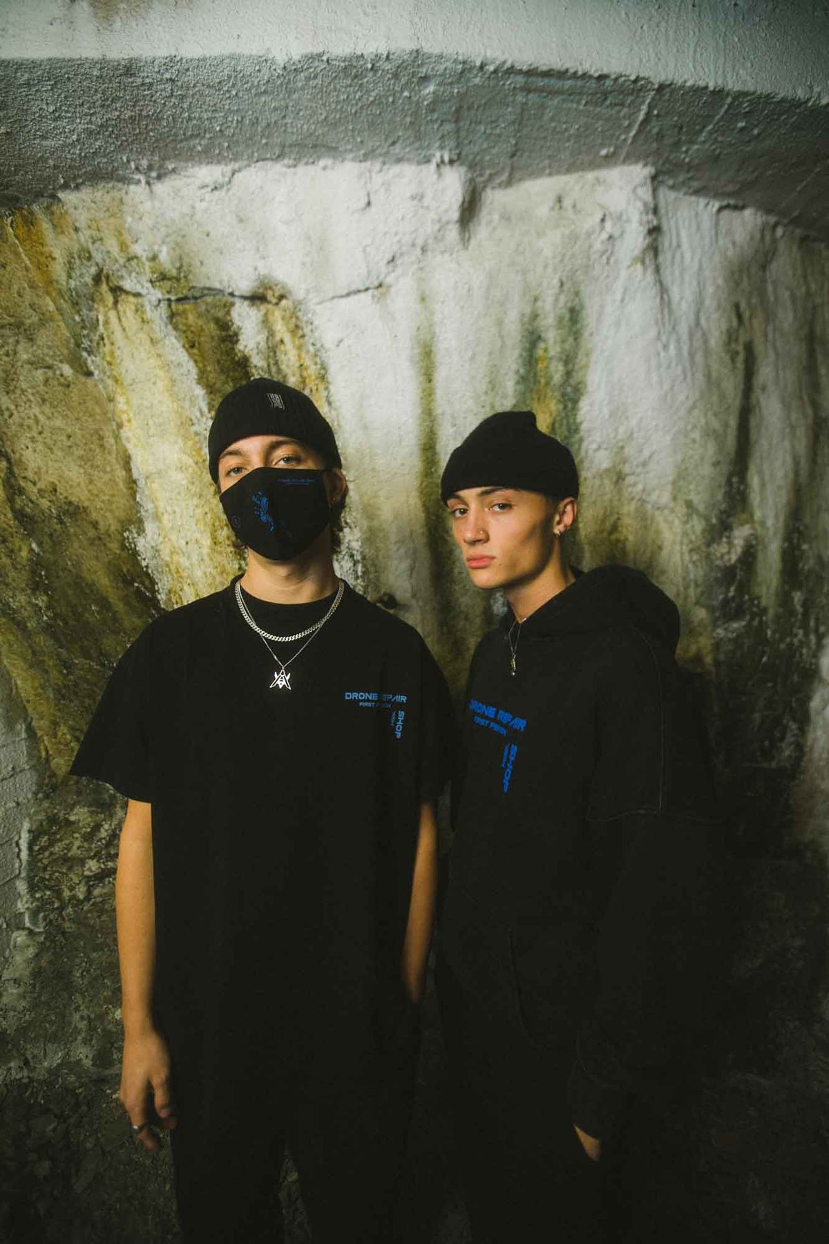 Alan Walker Drone Repair Shop T-Shirt in a lifestyle shot with two models in black, EDM streetwear styling