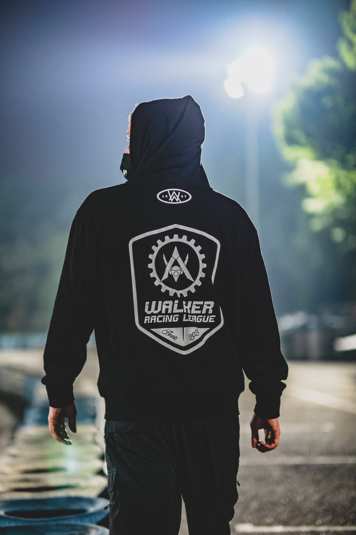 Alan Walker WRL Team Zip Hoodie worn hood up by a model on a floodlit kart track, white racing crest on the back