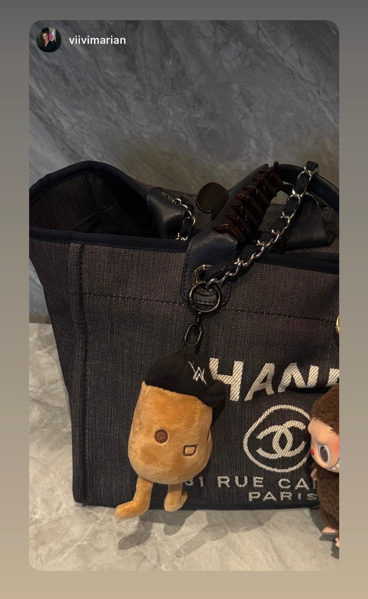 Alan Walker Tato Plushie clipped to a handbag in a lifestyle shot, small brown plush charm with AW cap