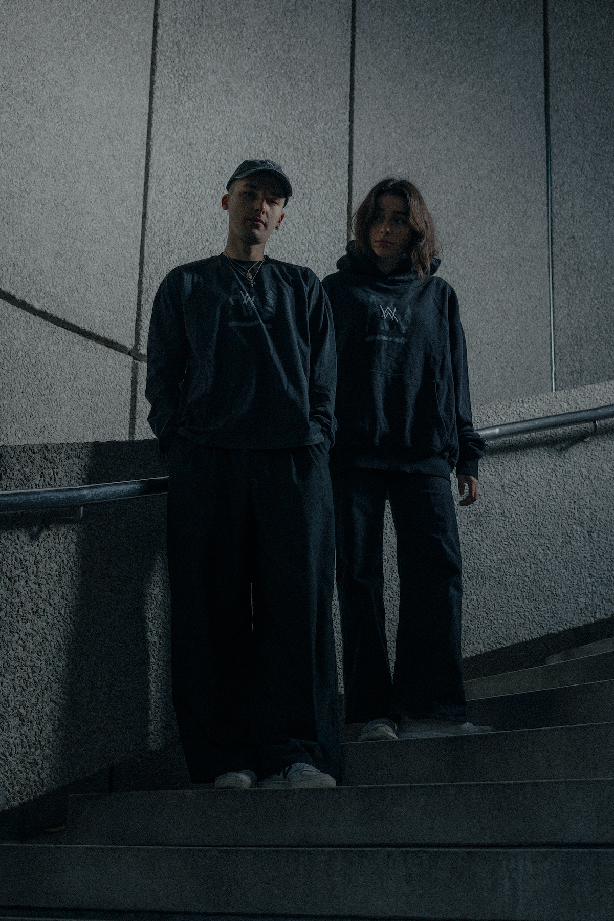 Alan Walker Faded Logo Cap in a night lifestyle shot, two friends in dark Walker apparel on concrete steps