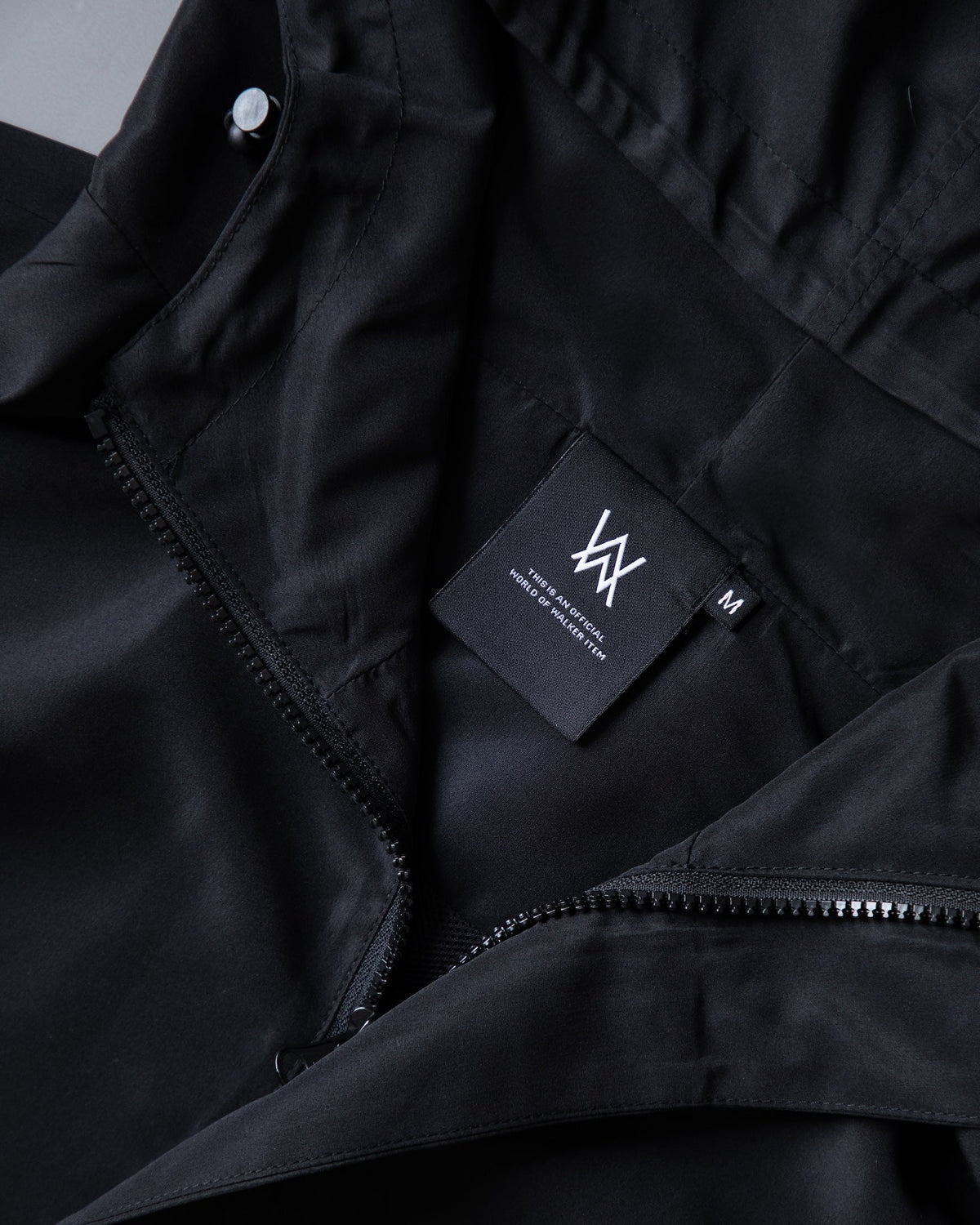 Alan Walker Core LV1 Windbreaker inner collar, woven AW size M tag beside the full length front zip