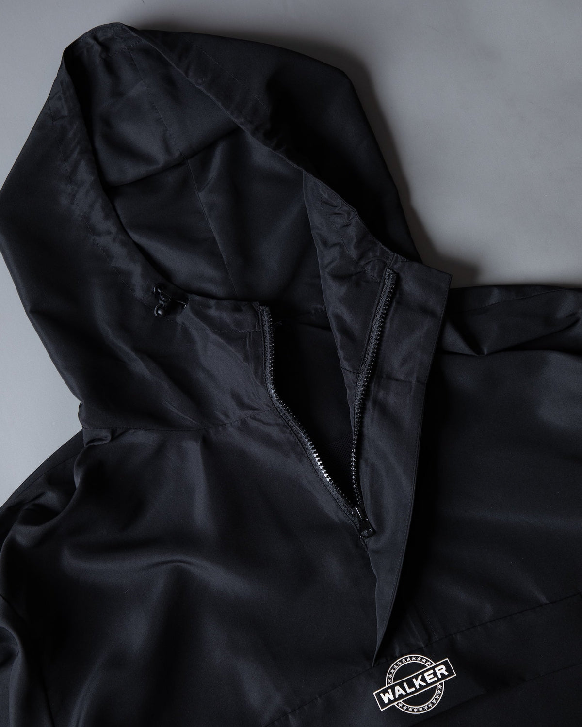 Alan Walker Core LV1 Windbreaker hood and zip laid flat, Walker stamp logo printed on the black hem