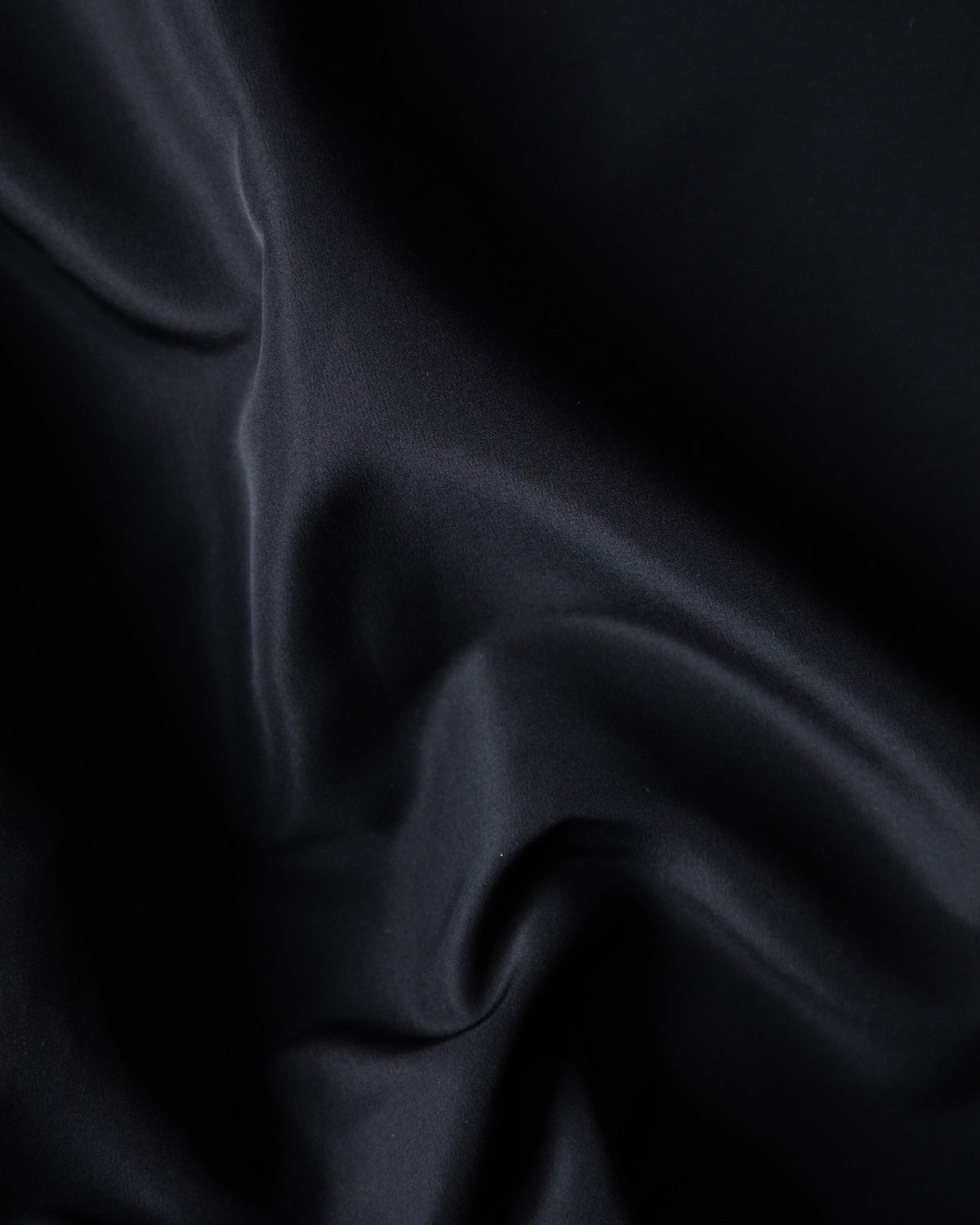 Alan Walker Core LV1 Windbreaker fabric close-up, softly folded matte black weather resistant shell