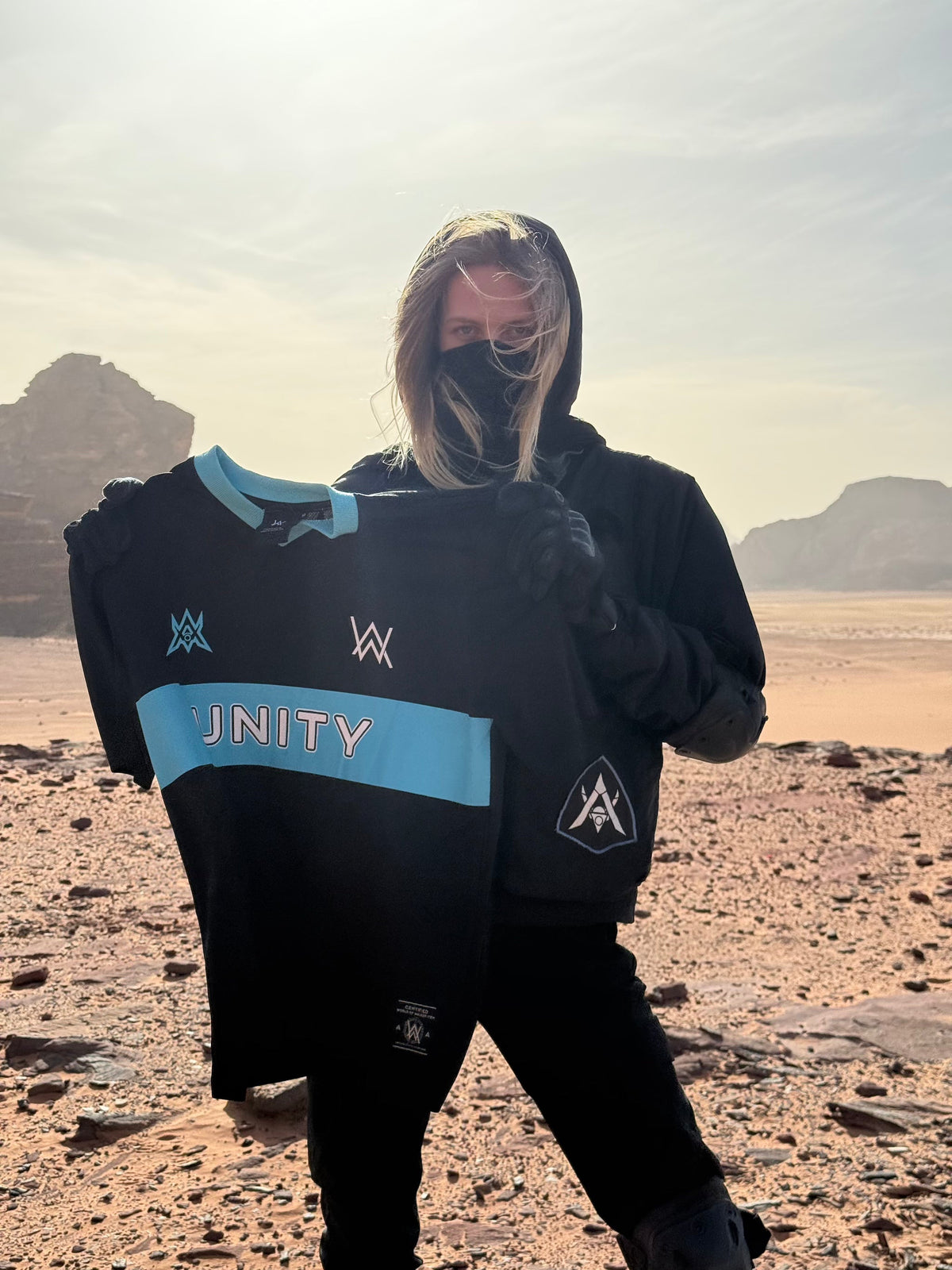 Alan Walker Unity Force Tribe Jersey held up by a masked fan in a desert landscape