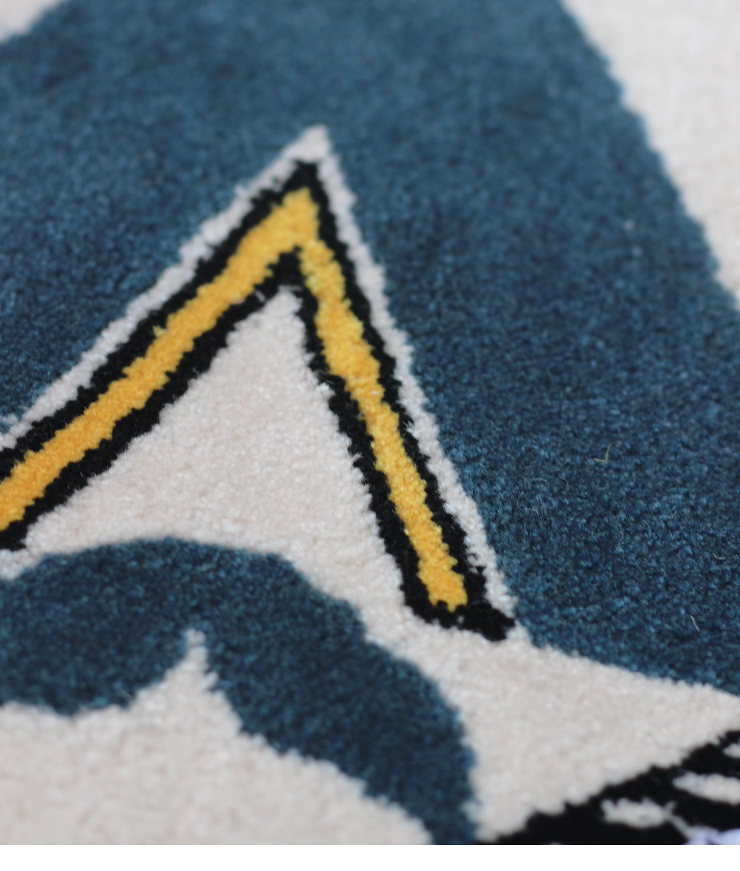 Alan Walker AV8 Rug pile close-up, yellow outlined teal chevron of the AV8 emblem in dense soft tufting
