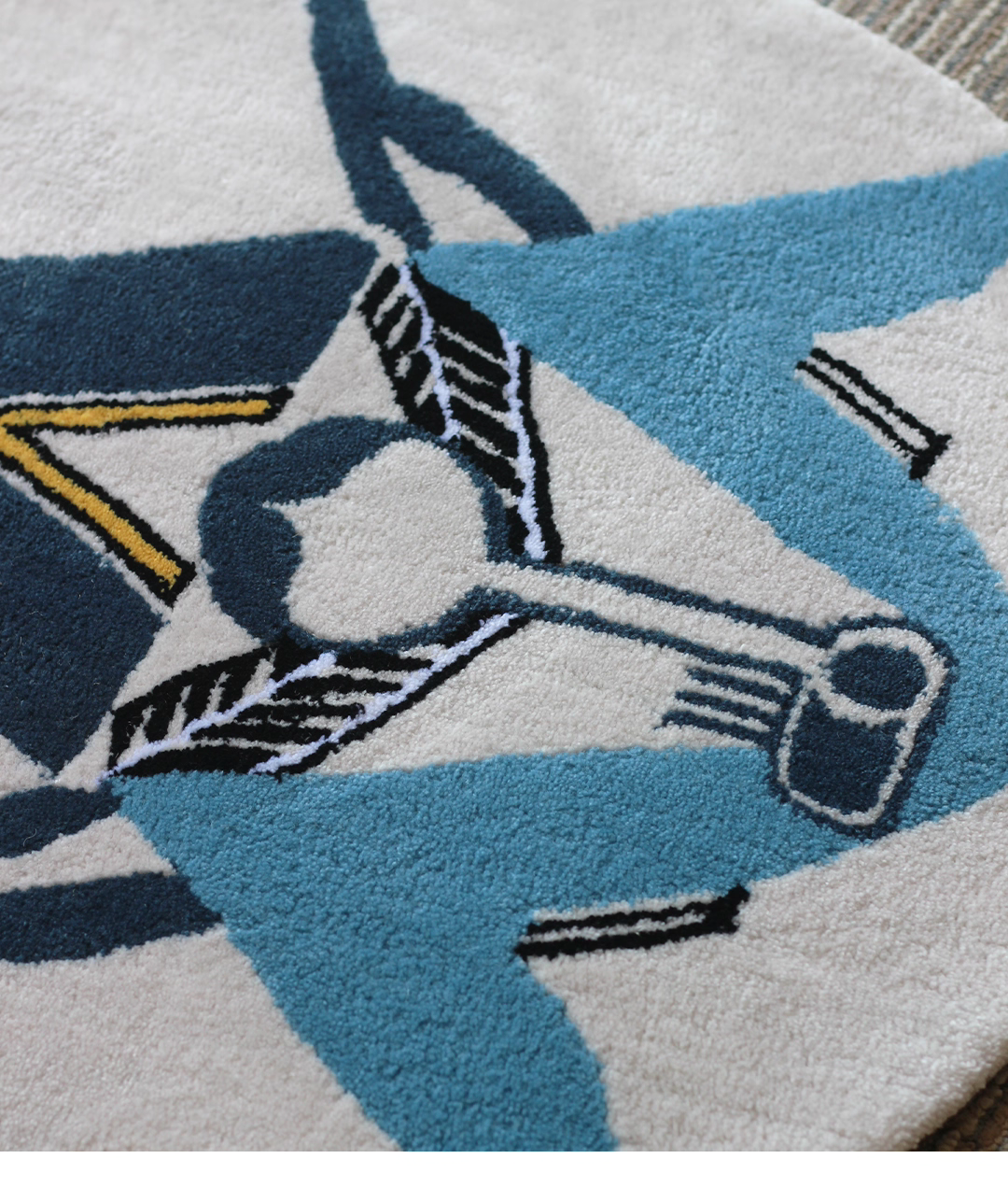 Alan Walker AV8 Rug detail on a floor, layered teal and sky blue wings around the central AV8 motif