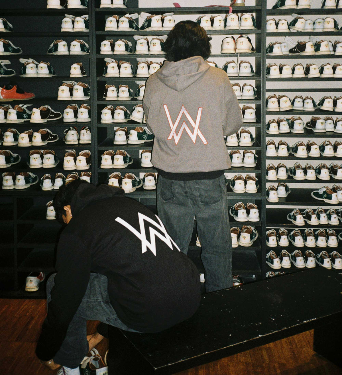 Alan Walker Core Logo Hoodie in grey and black worn in a shoe store, two fans showing the large AW back logo by the racks