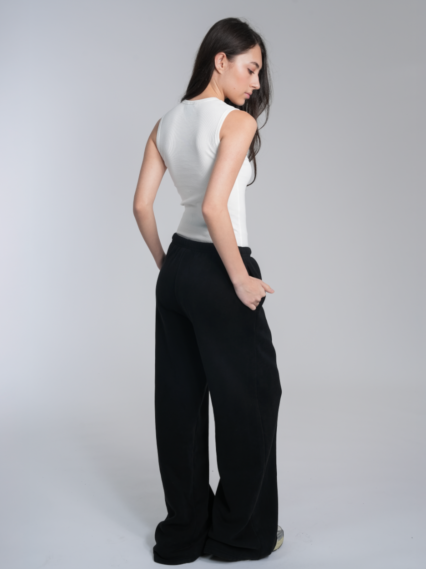 Alan Walker Core Sweatpants on a model from behind, black wide-leg fit styled with a white fitted top