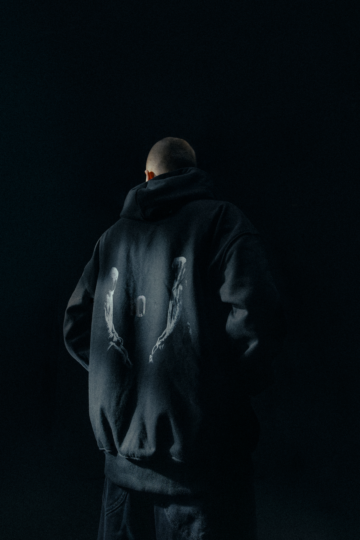 Alan Walker Tired 0 Hoodie worn from behind in low light, oversized black fleece with the Tired zero print