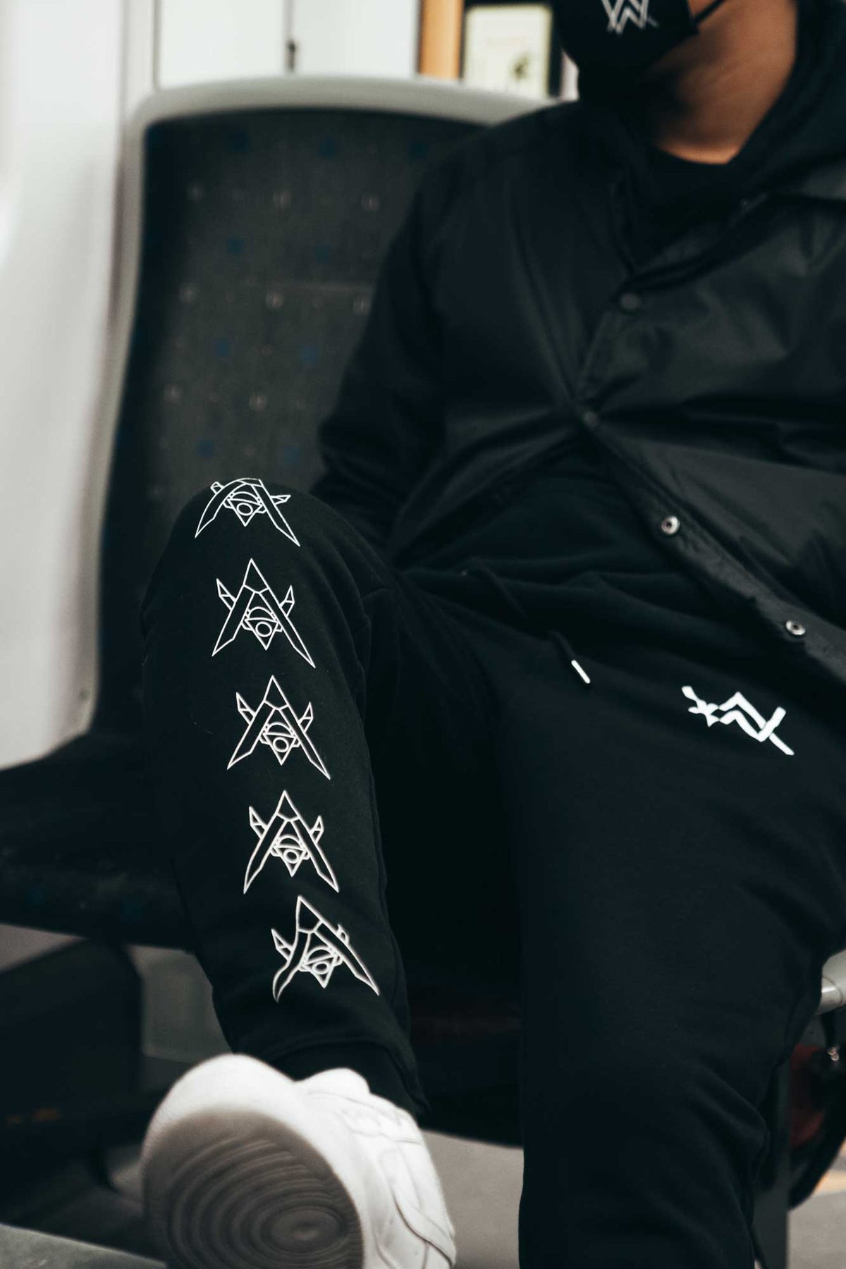 Alan Walker Core Drone Sweatpants worn seated, white drone graphics along the leg and AW print on the thigh