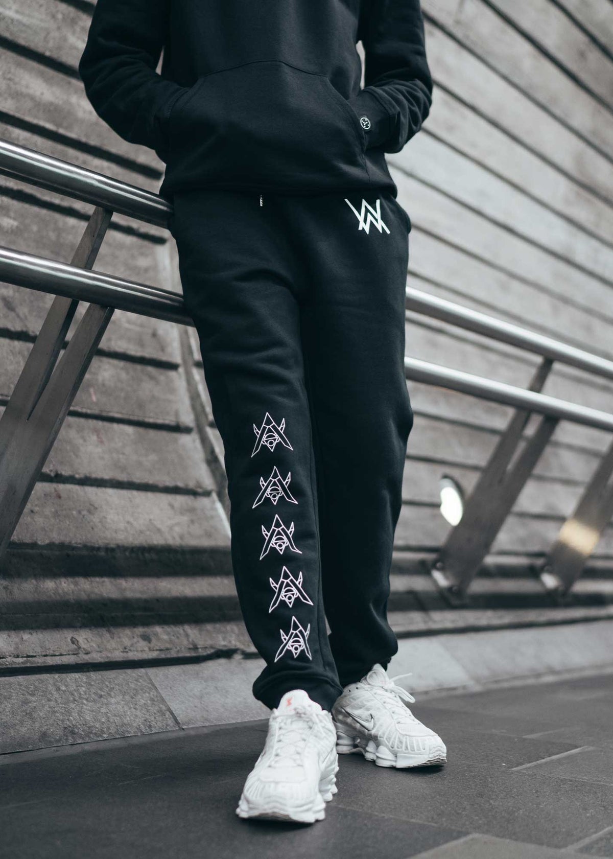 Alan Walker Core Drone Sweatpants worn on the street, drone icons running down the leg above white sneakers