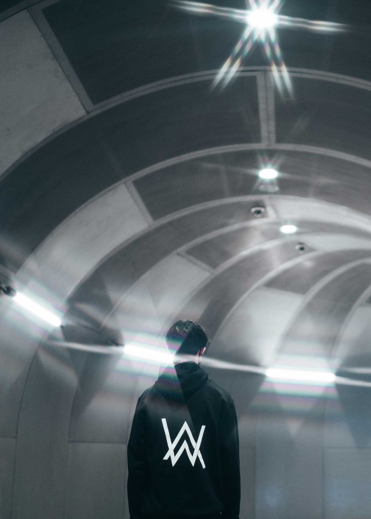 Alan Walker Core Logo Zip Hoodie in a bright tunnel, back view of the white AW logo on black fleece