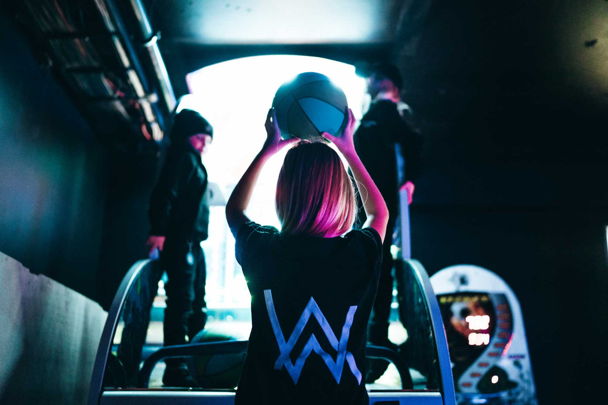 Alan Walker Kids Logo T-Shirt in a lifestyle shot, glowing blue AW logo on the back under tunnel light