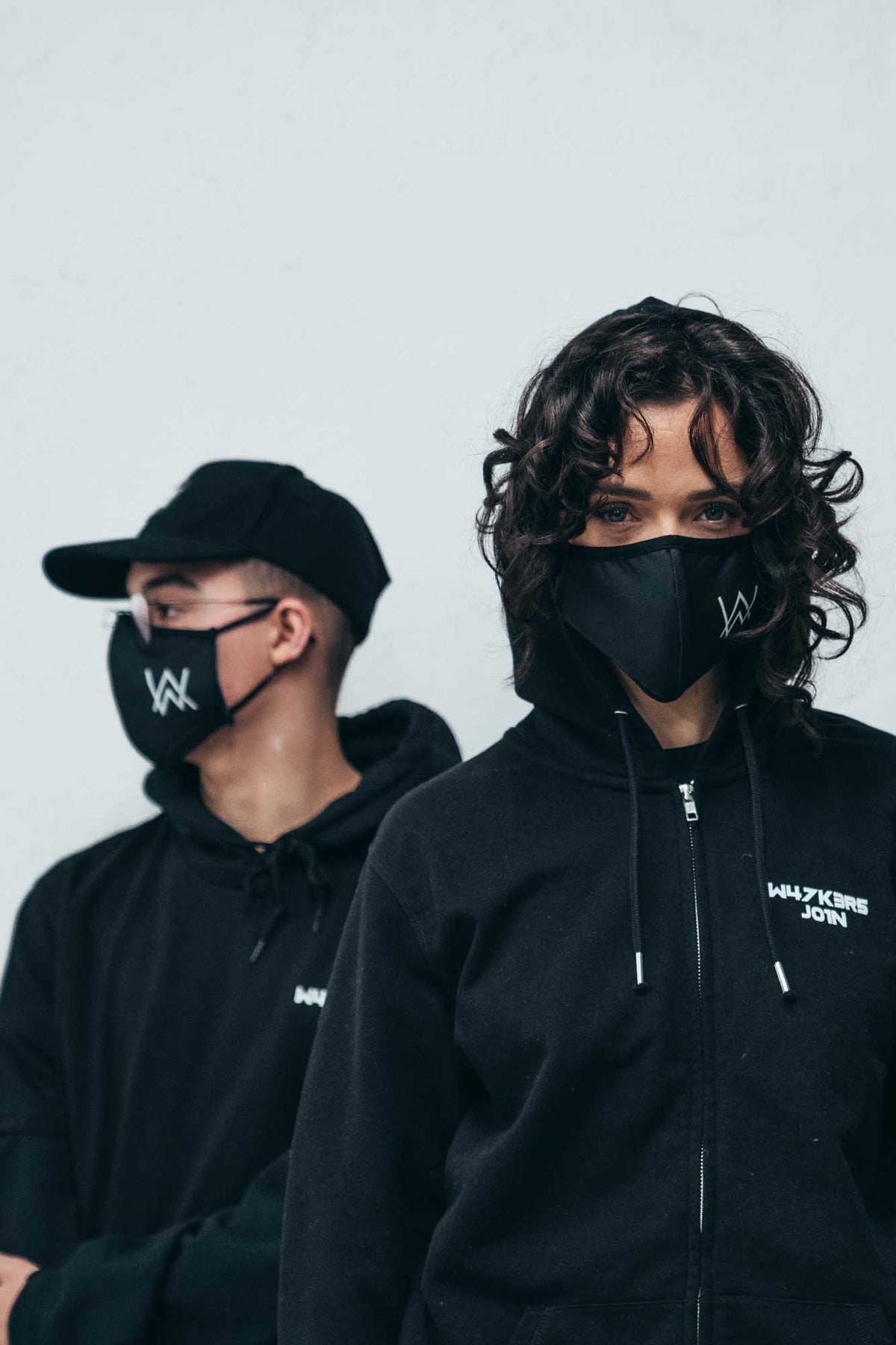 Alan Walker Core Logo Face Mask worn by two fans in black hoodies, white AW logo across the black fabric