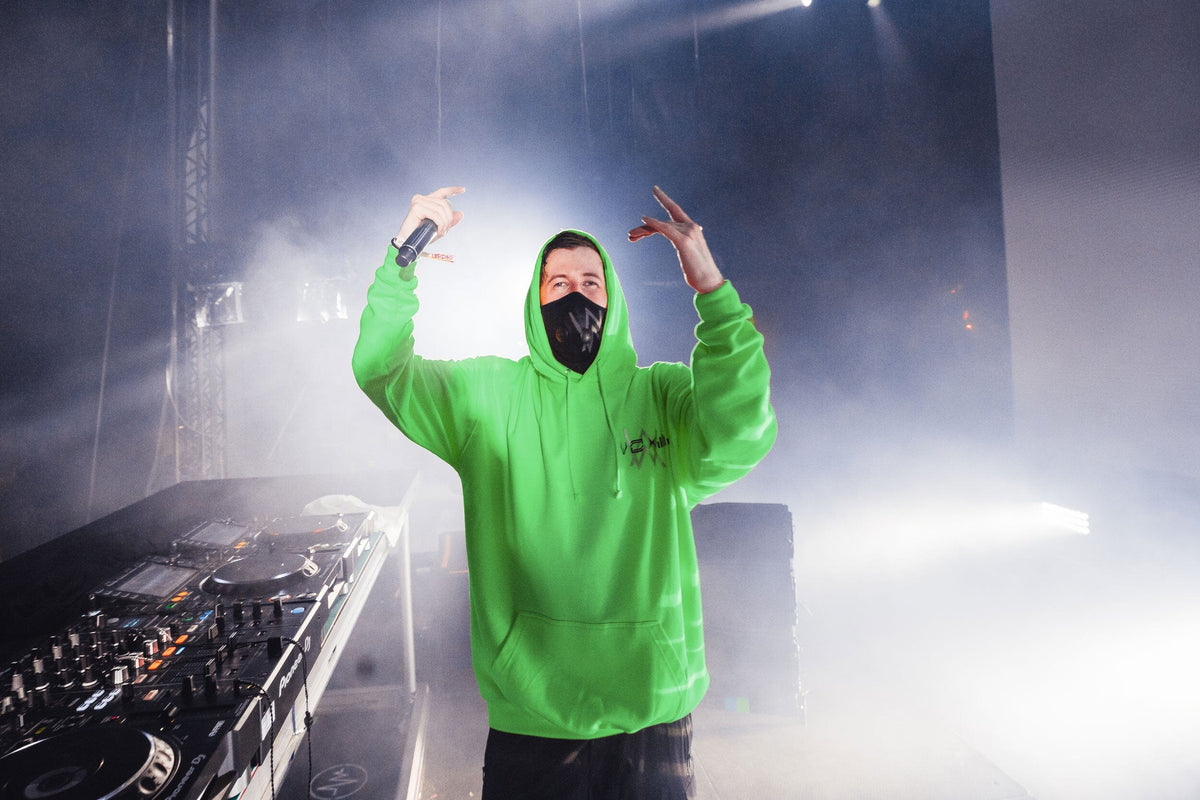 Alan Walker Stage Hoodie in green worn on stage by the masked DJ, arms raised behind the decks in smoke