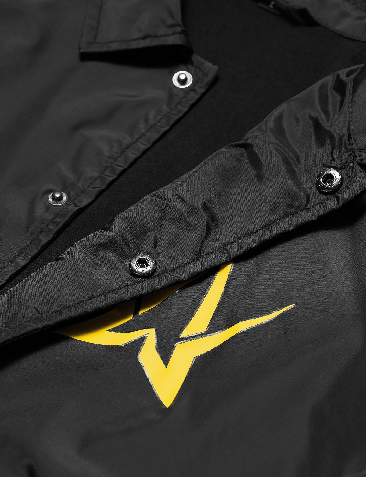 Alan Walker Walkerverse Crew Jacket open placket detail, metal snap buttons above the yellow logo print